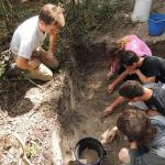 UoB student, Jack Fuller, teaching the CHSS students how to trowel a trench. 2014