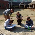UoB graduate student, Henry Webber, teaching 2 CHSS DECA students how to plot coordinates of the auger holes and trench site. 2014